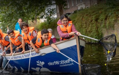 Children wearing life jackets collect plastic waste from an Amsterdam canal aboard a Plastic Whale Foundation boat.