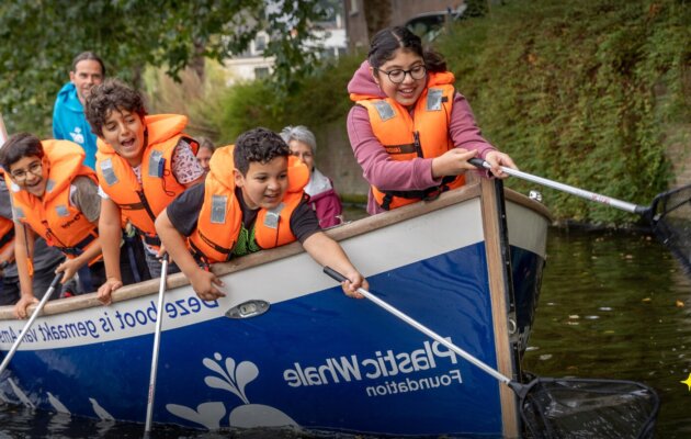 Children wearing life jackets collect plastic waste from an Amsterdam canal aboard a Plastic Whale Foundation boat.