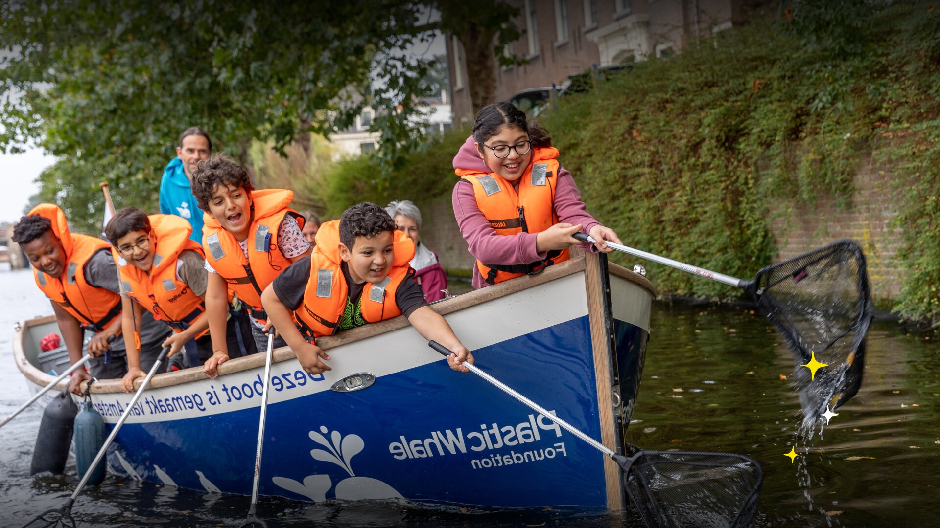 Children wearing life jackets collect plastic waste from an Amsterdam canal aboard a Plastic Whale Foundation boat.
