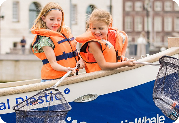 Two children fishing plastic from a boat